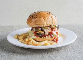 picante carne de vaca jalapeño hamburguesa con papas fritas servido en un plato aislado en gris antecedentes lado ver de rápido comida foto