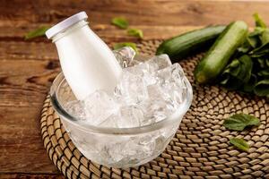 A bottle of AYRAN YOGHURT DRINK served in iced cube bowl side view on grey background photo