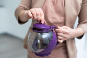 Female hand holding teapot isolated on white background. photo