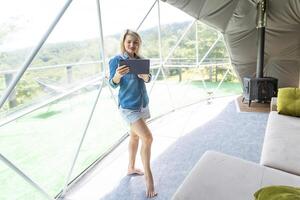 woman with tablet in dome tent. Glamping vacation lifestyle concept. photo