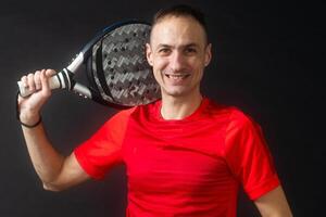 Smiling man with racket and paddle ball dressed in sport clothes isolated background. Front view. photo