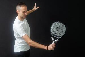 padel tenis jugador con raqueta en mano. paleta tenis, en un negro antecedentes. foto