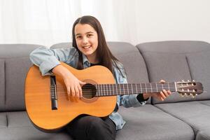 Portrait of smiling teen student practicing guitar during music lessons photo