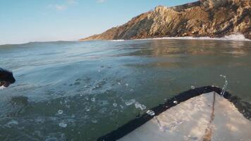 Surfer on surfboard riding on a crashing wave. First-person view of surfing in ocean at sunrise video