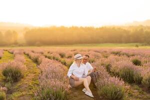 Handsome man with attractive woman lying down on fresh lavender field, enjoying each other, romantic relationship, love concept photo