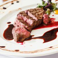 AI generated Roast beef steak lightly done, grilled on a white plate with sauce, herbs and tomatoes. AI generated. photo
