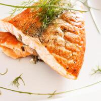 AI generated Grilled salmon fillet on a white plate with lemon or lime wedges, sauce and herbs. AI generated. photo