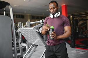 happy young african man drinking water after exercise photo