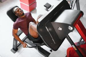 africano americano joven hombre haciendo rutina de ejercicio a el gimnasio foto