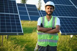 An Indian worker in uniform and with tools works on a solar panel farm photo