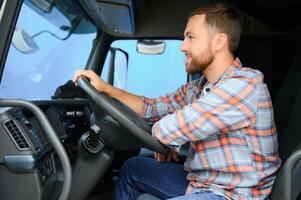 Side view of professional driver behind the wheel in truck's cabin. photo