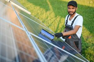 Indian handyman cleaning solar panels form dust and dirt. photo