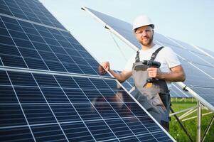 Side view of male worker installing solar modules and support structures of photovoltaic solar array. Electrician wearing safety helmet while working with solar panel. Concept of sun energy photo