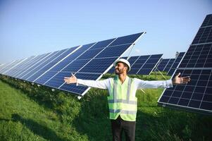 retrato de joven indio masculino ingeniero en pie cerca solar paneles, con claro azul cielo fondo, renovable y limpiar energía. habilidad India, Copiar espacio. foto