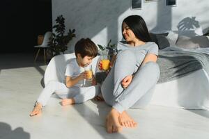 mom with son in pajamas drinking juice in the morning in bed. Healthy eating concept photo