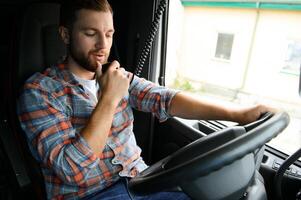 hombre camionero conducción en un cabina de su camión y hablando en radio transmisor. foto