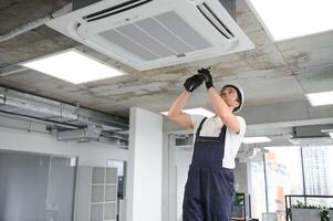 Electrician repairing air conditioner indoors photo