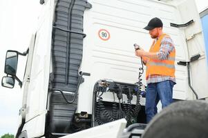View of a driver connecting the power cables to trailer of a commercial truck. photo