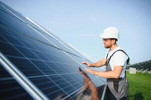 Side view of male worker installing solar modules and support structures of photovoltaic solar array. Electrician wearing safety helmet while working with solar panel. Concept of sun energy photo