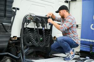 View of a driver connecting the power cables to trailer of a commercial truck. photo