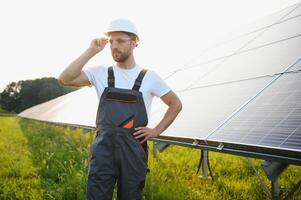 lado ver de masculino trabajador instalando solar módulos y apoyo estructuras de fotovoltaica solar formación. electricista vistiendo la seguridad casco mientras trabajando con solar panel. concepto de Dom energía foto