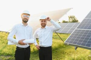 el solar granja solar panel con dos ingenieros caminar a cheque el operación de el sistema, alternativa energía a conservar el del mundo energía, fotovoltaica módulo idea para limpiar energía producción foto