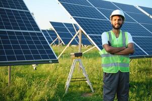 Male arab engineer standing on field with rows of solar panels. photo