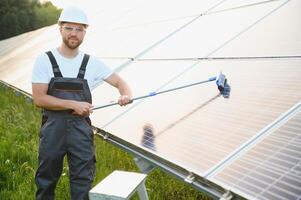 Worker cleaning solar panels after installation outdoors. photo