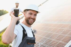 Ingenieria equipo trabajando en comprobación y mantenimiento en solar poder planta, solar panel técnico instalando solar paneles en techo en un soleado día foto