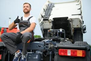 Semi Truck Under Maintenance. Caucasian Truck Mechanic Working to Fix the Tractor. photo