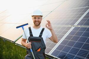 A handyman cleaning solar panels form dust and dirt. photo