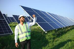 retrato de joven indio masculino ingeniero en pie cerca solar paneles, con claro azul cielo fondo, renovable y limpiar energía. habilidad India, Copiar espacio. foto