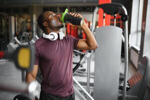 happy young african man drinking water after exercise photo