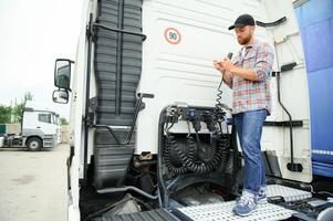 View of a driver connecting the power cables to trailer of a commercial truck. photo