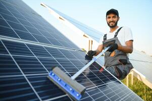 Male arab engineer standing on field with rows of solar panels. photo