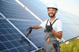 An Indian male worker is working on installing solar panels in a field photo