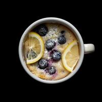 AI generated Photo of a blueberry lemon cake in a mug isolated on a black background