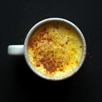 AI generated Top view of turmeric milk cake in a mug on a dark background photo