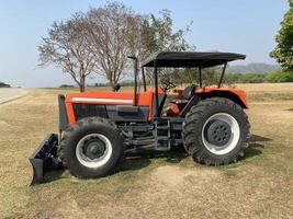 Red tractor working in green field no people. photo