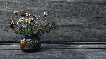 Wild flowers in the ceramic vase in the wooden table photo