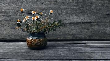 Wild flowers in the ceramic vase in the wooden table photo