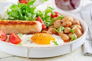 English breakfast. Keto breakfast. Fried egg, beans, chicken sausage and coffee cup. photo