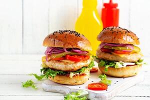 Chicken hamburger. Sandwich with chicken burger, tomatoes, cheese, pickled cucumber and lettuce. Cheeseburger. photo