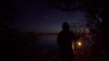 dunkel Nacht einsam Frau mit ein Lampe steht auf das Banken von das Fluss video