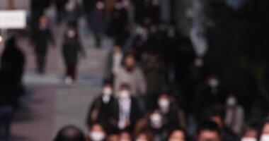 A crowd of walking people on the city street defocused video