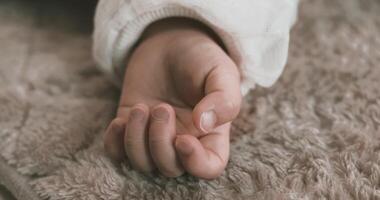 une la gauche main de en train de dormir asiatique bébé sur le tapis ordinateur de poche video