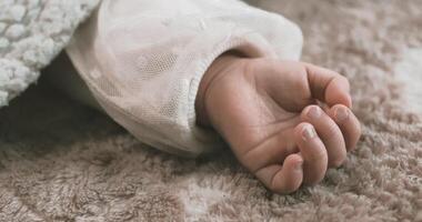 A left hand of sleeping asian baby on the carpet handheld video