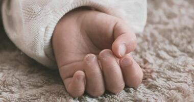 A 2x slow motion of sleeping asian baby left hand on the carpet handheld video