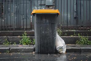 ai generado grande basura lata soportes en el calle siguiente a cerca foto