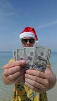 Man wearing Santa hat counting US dollars on tropical beach video